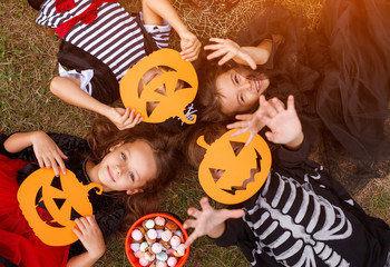 Happy kids with pumpkin masks relaxing on grass