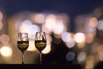 Pair of wine glasses on table against bokeh lights. 