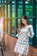 Business women and coffee cups using phones on the side of the coffee shop