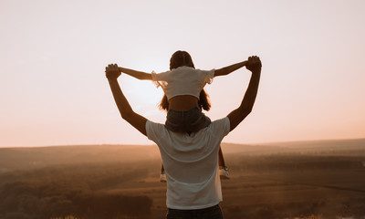 Anonymous father with daughter during sunset in nature
