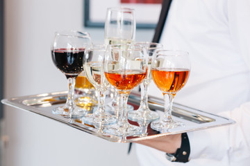 Waiter serving glasses of cold beer, soft drinks and white wine on the tray at a business meeting
