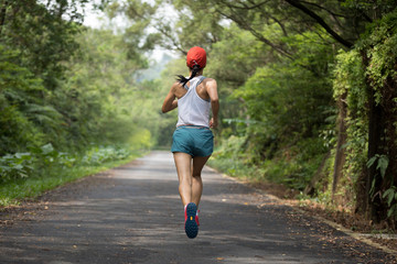 Female runner running at summer park trail . Healthy fitness woman jogging outdoors.