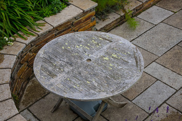 A weathered circular wooden garden table