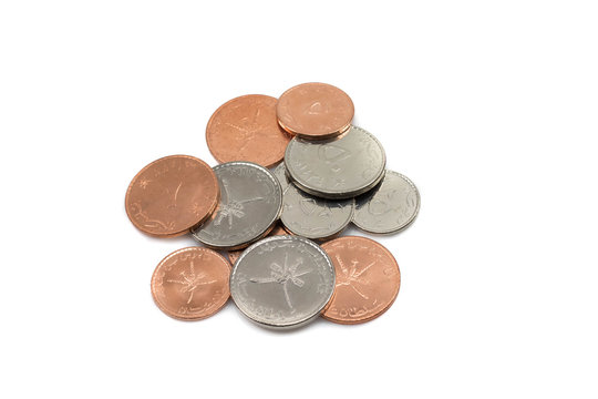 A close up photo of a pile of coins from Oman isolated against a clean, pure white background
