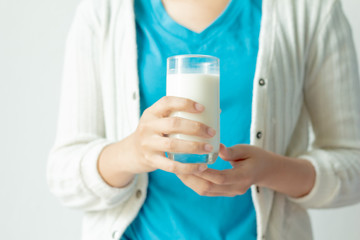 Woman hand holding glass of fresh milk on white background.