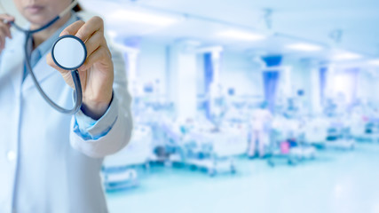 Medical doctor holding stethoscope in hand against blurred intensive care unit ( ICU.) background. 