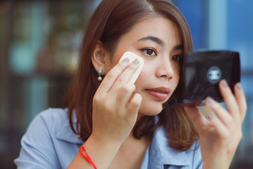Asian woman make up her face with lipstick in cafe