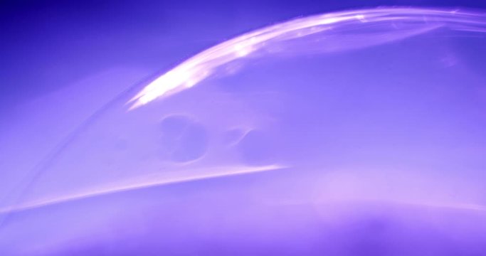 macro shot of a purple sphere glowing in the dark. Little particles moving in the current of the sphere. Light moving.
