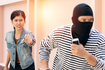 Thief dangerous man or robber in black and white shirt with masked threatening to steal items from...