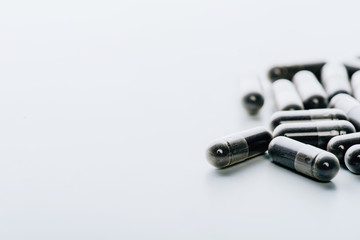 selective focus of black pills on white background with copy space