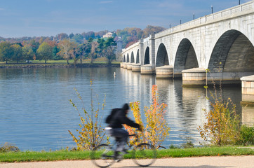 A biker riding next to Memorial Bridge in autumn foliage - Washington D.C. United States of America