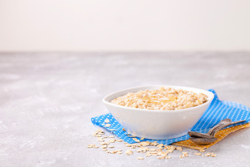 Porridge with oil in a bowl on a gray concrete background. Healthy useful breakfast. Selective focus. Copy space