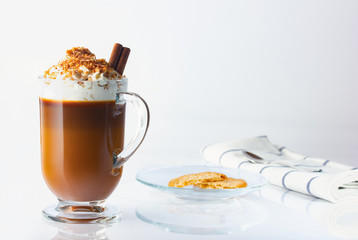 Cappuccino in a glass, Irish glass, cinnamon stick, ground nut and chocolate chips. Halved oatmeal cookies in a glass plate. Coffee spoon on linen napkin. The photo.