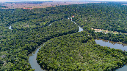 Aerial view of a meandering Amazon tributary river, agricultural land at the horizon Amazonian rainforest, San Jose do Rio Claro, Mato Grosso