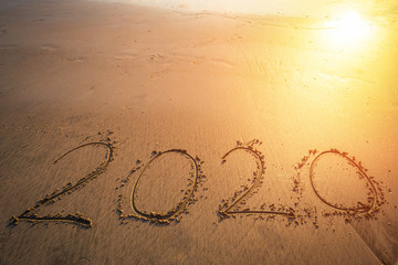 Happy New Year 2020 text on beautiful the sea beach with wave early morning sunrise over the horizon background.During Christmas and New Year.