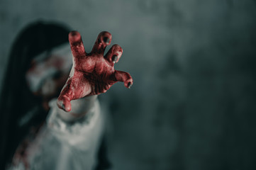 Horror ghost woman stretches her hand with resentment, has blood in hand, Halloween murder concept.