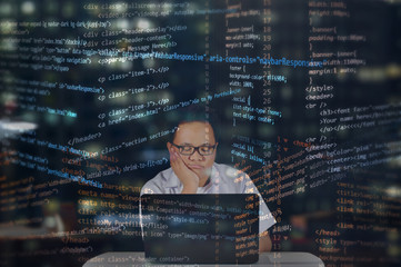 Sleepy IT student working in his laptop while writing codes for web development. Working at night with random HTML codes surrounding the web designer concept. 