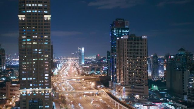 Skyline internet city with crossing Sheikh Zayed Road aerial night view. Illuminated skyscrapers with traffic on a highway and metro line in Dubai