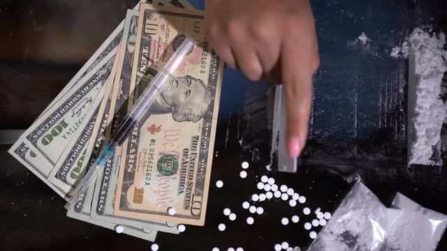 White cocaine powder on a table with dollar bills and a syringe