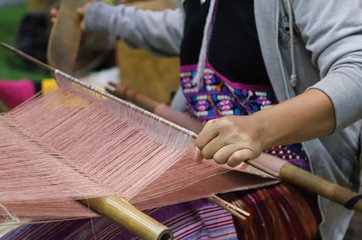 Closeup of skillful woman's hand doing colorful cotton cloth weaving.