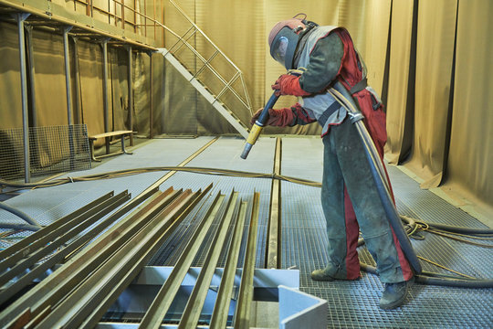 Sandblasting In Chamber. Worker Makes Sand Blast Cleaning Of Metal Detail