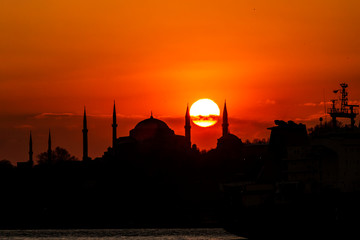 Obraz premium Cityscape of Istanbul with silhouettes of ancient mosques and minarets at sunset. Panoramic view, The Maiden's Tower, Galata Tower, Hagia Sophia, The Blue Mosque and Topkapı Palace in Istanbul.
