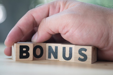Block in word BONUS in man hand