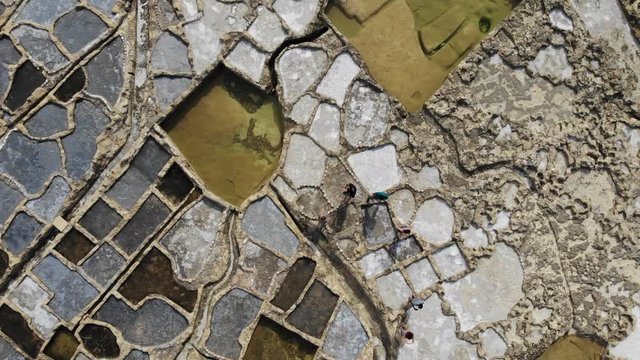 People walk among the 300-year-old sea salt harvesting salt pans on the island of Gozo in the Malta Archipelago, as see from above by drone.