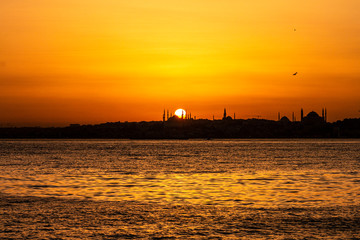 Cityscape of Istanbul with silhouettes of ancient mosques and minarets at sunset. Panoramic view, The Maiden's Tower, Galata Tower, Hagia Sophia, The Blue Mosque and Topkapı Palace in Istanbul.