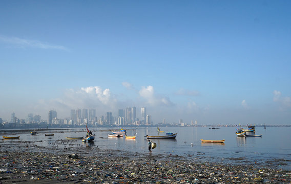 A ragpicker collects recyclable material from a garbage-strewn beach in Mumbai