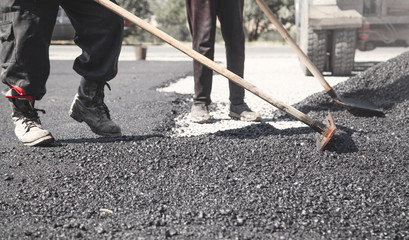Workers arranging asphalt. Road construction. Industry