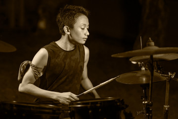 Asian American mixed teenager playing drums at home garden . cool and handsome young boy practicing on drum kit rehearsing passionate in badass rock band look