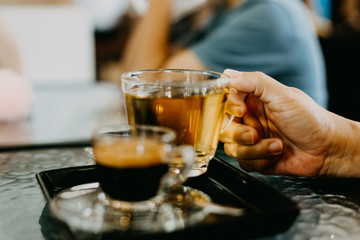 Selective focus hand holding tea glass and hot espresso coffee menu in coffee shop.Hot drink menu for customer in the cafe.Different drinking menu concept.