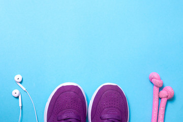 headphones, sneakers, jump rope on blue background flat lay