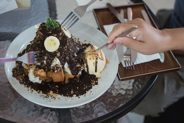 Selective focus ice cream cake with enjoying family eat honey banoffee toast menu in white dish on table at restaurant.Eating party concept.