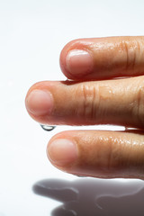 Woman's wet right hand with water drops on middle finger,  White acrylic background, Close up & Macro shot, Selective focus, Asian Body skin part, Relaxing Bath, Healthcare concept