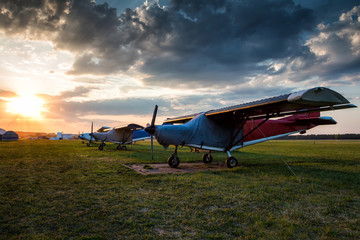 Fototapeta na wymiar Small private airplanes parked at the airfield at picturesque sunset