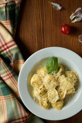 Fresh, homemade italian Ravioli with meat, decorated with parmesan and basil on a wooden background.