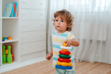 baby plays on the floor in the room in educational plastic toys.
