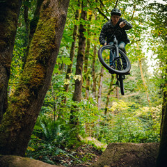 Man Jumping High on Dirt Mountain Bike Jump in the Woods
