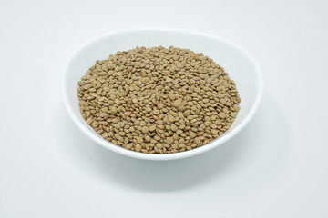 Isolated plate, full of uncooked lentil seeds.