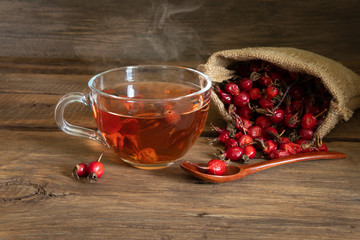 Rosehip tea on wooden background with red fruits
