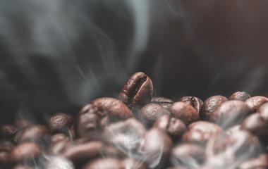 Aroma roasted coffee beans with smoke rising over dark background