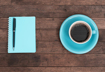 Blue coffee cup,pen and notebook on grunge wooden table top background,top view with copy space