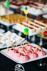 portions of mousse creamy desserts with chocolate. various snacks in three-storey services. Sweets, saltwater, cheese  balls, pickles, cheese tree, chocolate mousse, served on trays