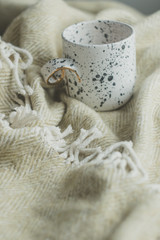 White cup in black dot on a warm cozy plaid.