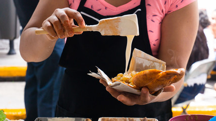 Cocinera tradicional mexicana poniéndole crema a un pambazo