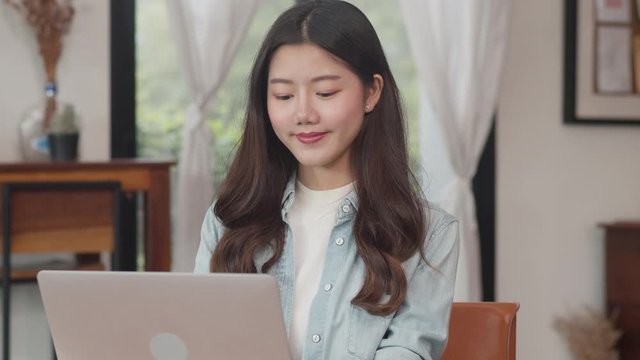 Young Asian freelance women working on laptop at coffee shop. Asian happy man barista waiter wear gray apon serve hot cup of coffee to female customer who business work in cafe or restaurant.