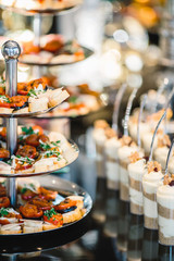 portions of mousse creamy desserts with chocolate. various snacks in three-storey services. Sweets, saltwater, cheese  balls, pickles, cheese tree, chocolate mousse, served on trays