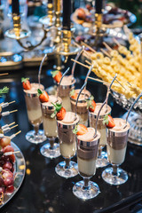 portions of mousse creamy desserts with chocolate. various snacks in three-storey services. Sweets, saltwater, cheese  balls, pickles, cheese tree, chocolate mousse, served on trays